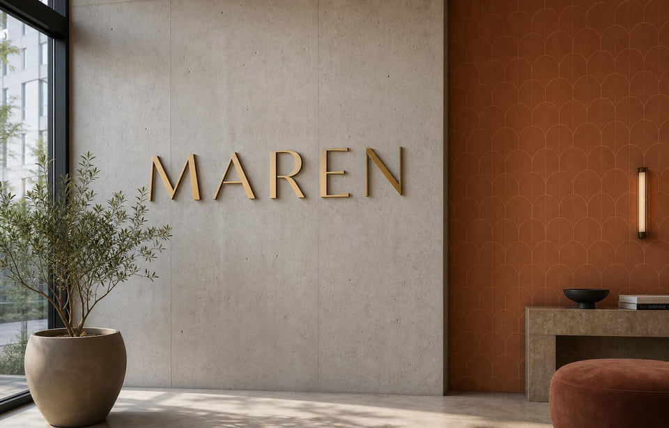 Maren brushed brass lobby signage on concrete wall with terracotta arch pattern